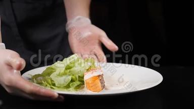 厨师在手套，翻盘与新鲜的三文鱼片，与蔬菜和生菜在白色盘子。 高清高清